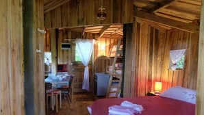 Una cabaña de madera con una cama, un escritorio con una computadora y una escalera.