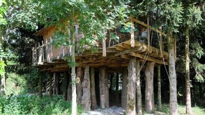 Una casa en los árboles de madera, elevada sobre pilotes, en un área boscosa.