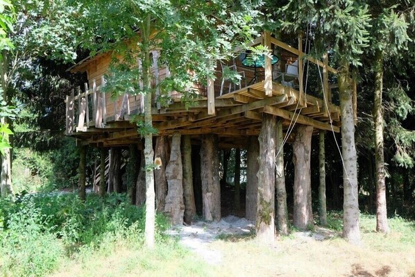 A wooden treehouse elevated on stilts in a forested area.