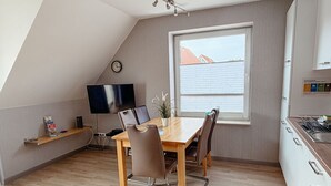 Une cuisine moderne avec une table à manger, des chaises, un téléviseur et une fenêtre donnant sur un beau paysage.