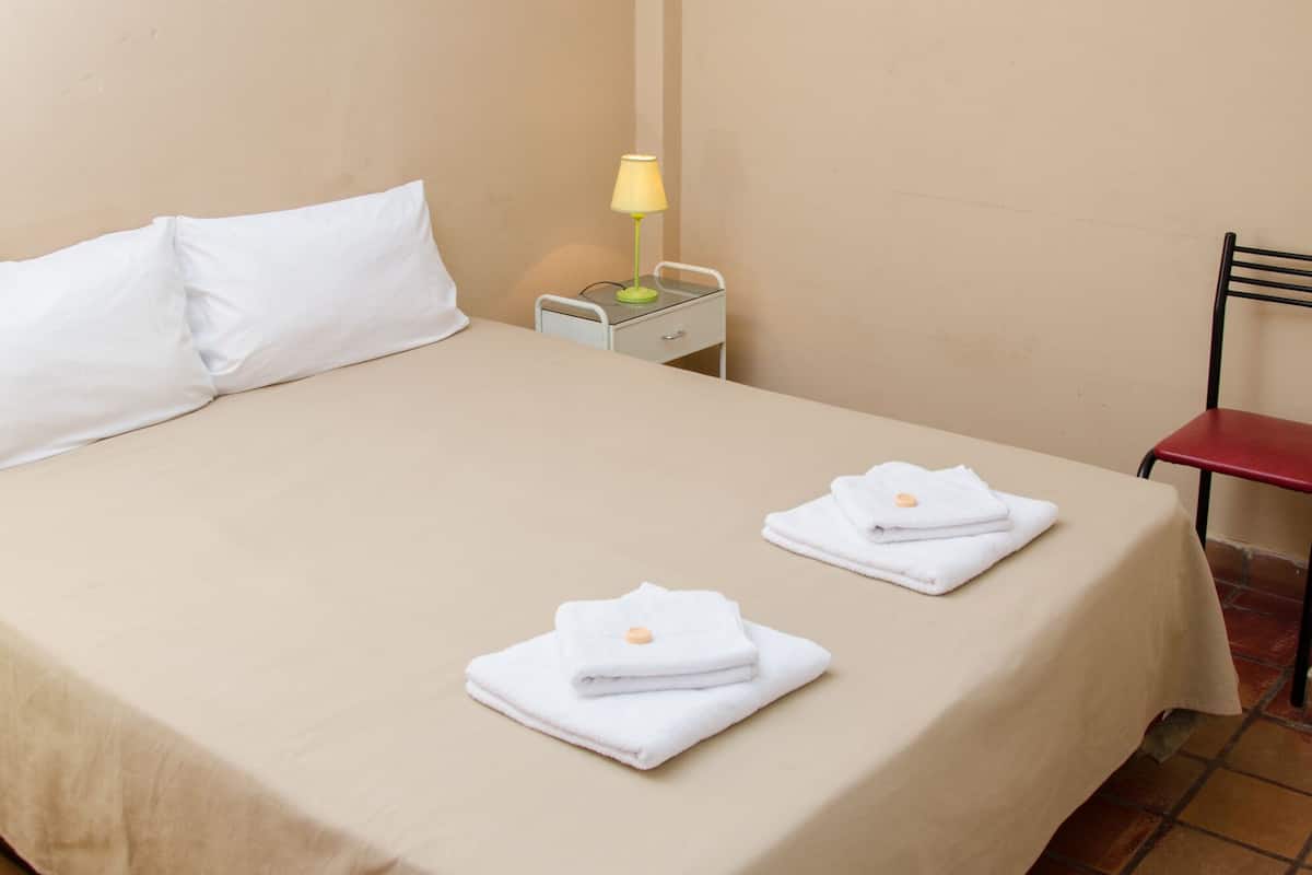 Une chambre d’hôtel avec un lit, une table de chevet, une lampe et une chaise.