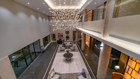 A spacious lobby with a central seating area, a high ceiling with hanging lights, and a modern design. - Belvedere Golf & Country Club (Gandhinagar)