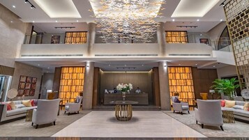 A spacious lobby with a reception desk, seating area, and a decorative ceiling feature.