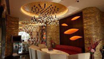 A modern hotel lobby with a central seating area, a decorative light fixture, and a reception desk.