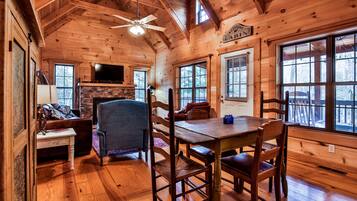 L’intérieur d’un chalet en bois comprend une table à manger, des chaises, un canapé et une cheminée.