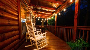 Eine Holzterrasse mit einem Schaukelstuhl und einem Blumentopf.