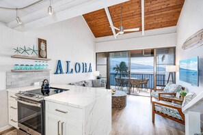A modern kitchen with a built-in oven and a dining area with a view of the sea.