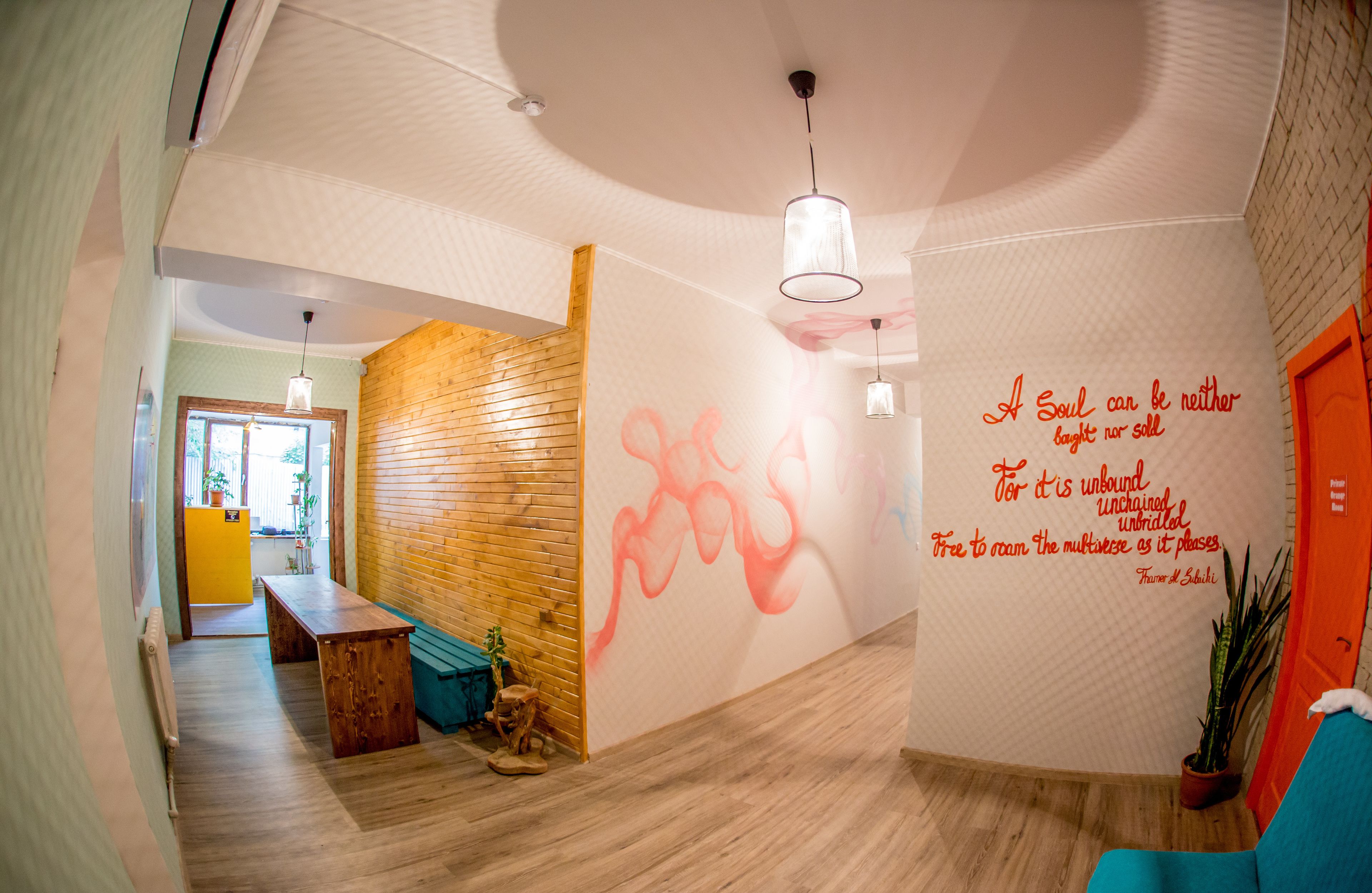 A modern interior with a wooden bench, a wall with a quote, and a wooden partition.