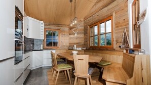 A wooden interior with a kitchen, dining area, and large windows.