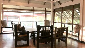 A spacious room with large windows, wooden flooring, and three wooden chairs with cushions. - C Donata Bed & Breakfast Guesthouse (Tagaytay)