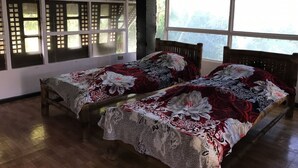 A room with two wooden beds, each with floral bedding, large windows, and a wooden floor. - C Donata Bed & Breakfast Guesthouse (Tagaytay)