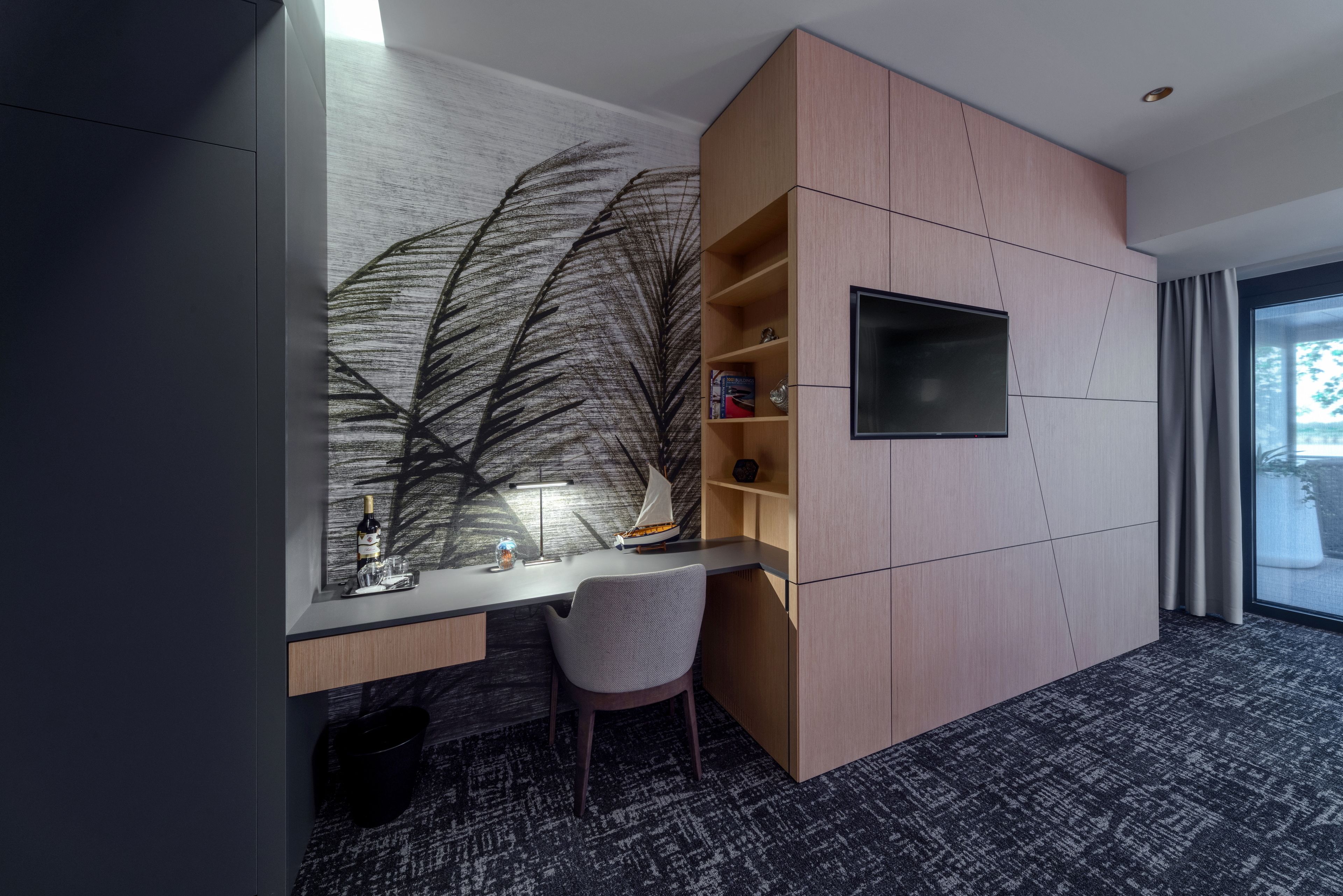 Una habitación de hotel moderna con escritorio, silla y un amplio ventanal.
