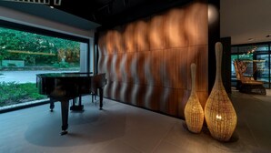 A modern interior with a grand piano, a textured wall, and decorative vases. - Donautica Hotel & Restaurant (Fadd)