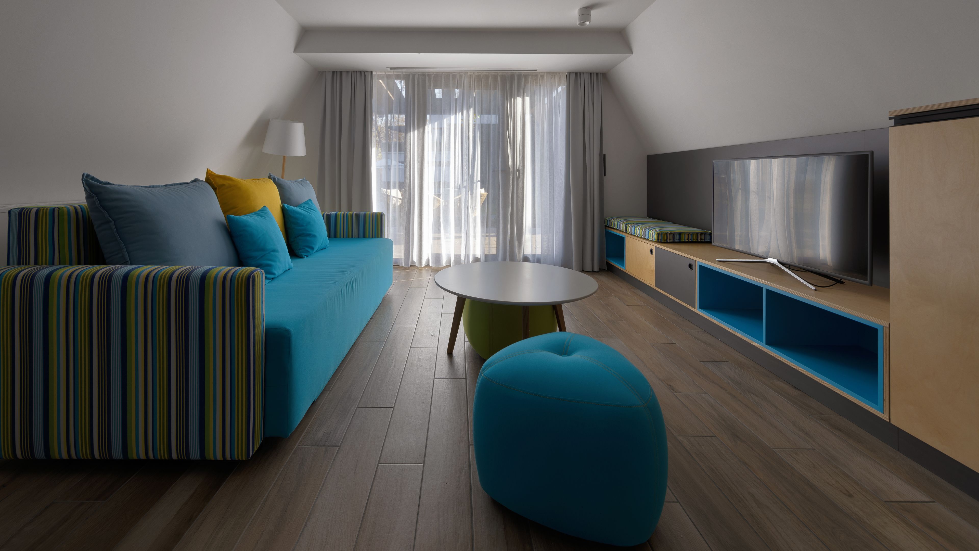 A modern living room with a sofa, ottoman, and TV.