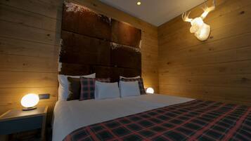 Een houten kamer met een bed, nachtkastjes en een opgehangen hertenkop.
