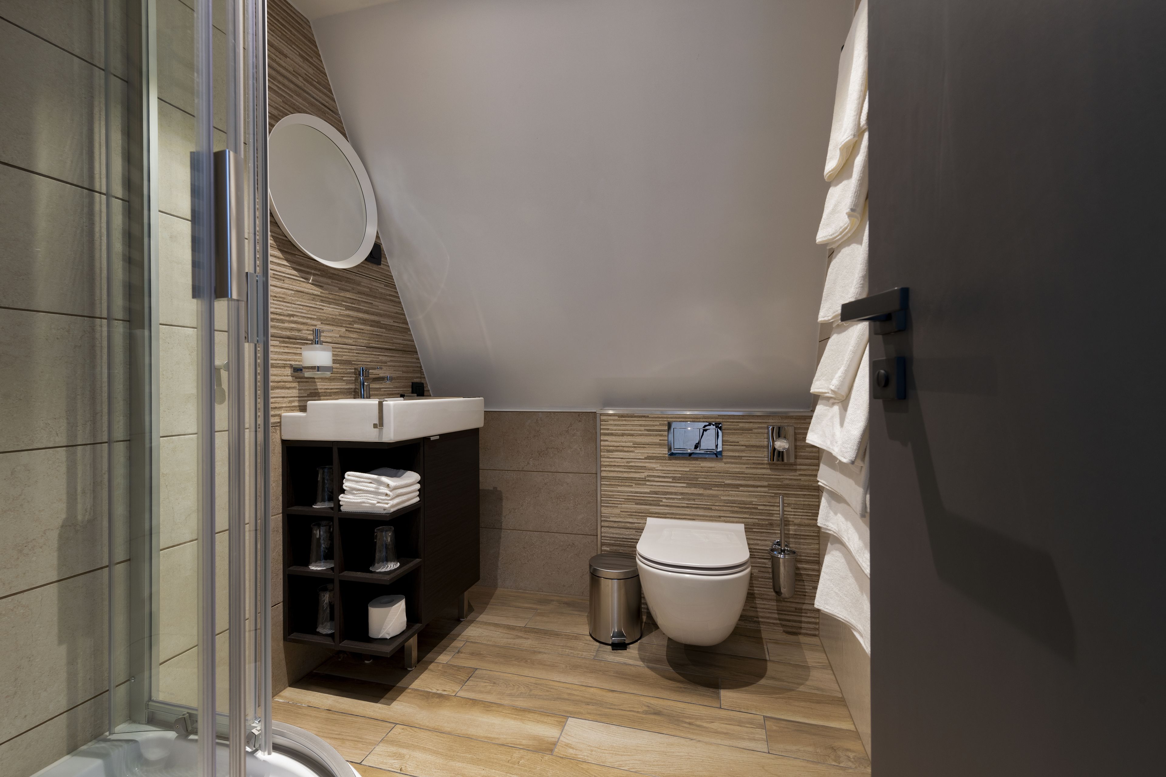 A modern bathroom with a glass shower enclosure, a sink, a toilet, and a towel rack.