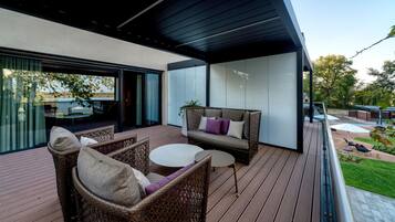 Eine moderne Terrassenanlage im Freien mit Korbmöbeln, einem runden Tisch und einer Couch mit Kissen.