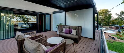 A modern outdoor patio with wicker furniture, a round table, and a sofa with cushions.