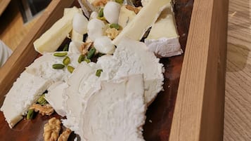 A wooden board with various cheeses and nuts.
