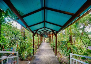 A covered walkway with a tiled floor, surrounded by lush tropical vegetation. - Pinpin d'Amour (Saint-Philippe)