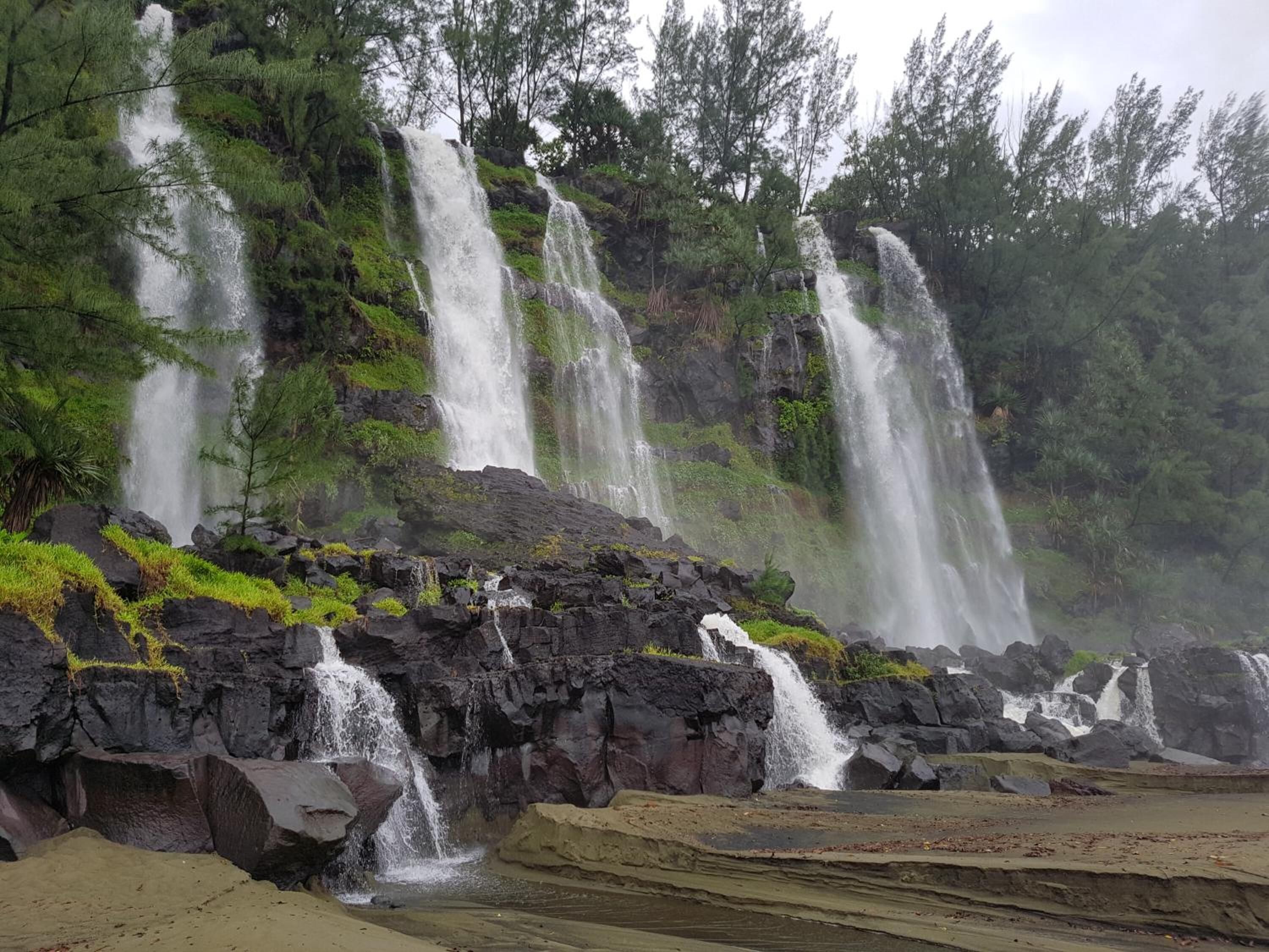 A waterfall cascading over rocks with a forested background.