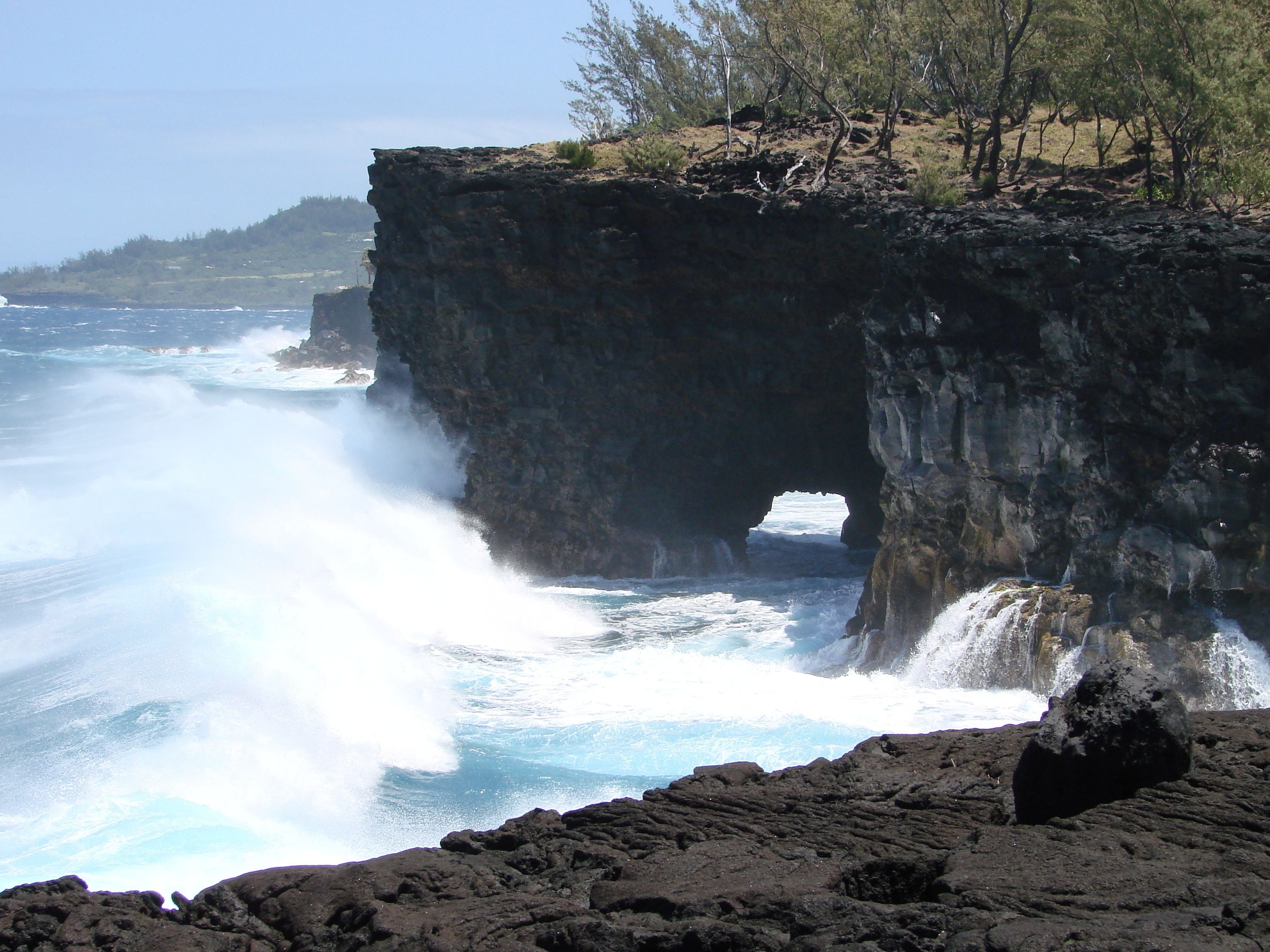 A coastal landscape with a prominent cliff and a sea cave.