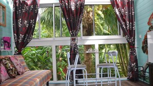 A room with a large window, a sofa, two chairs, and a small table. - Pinpin d'Amour (Saint-Philippe)