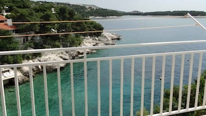 A coastal view with a clear sky, rocky shoreline, and a distant town.