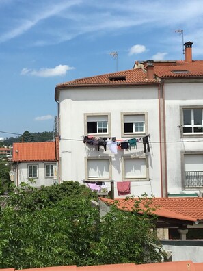 Un edificio de dos pisos con techo de tejas rojas, paredes blancas y un tendedero con varias prendas.