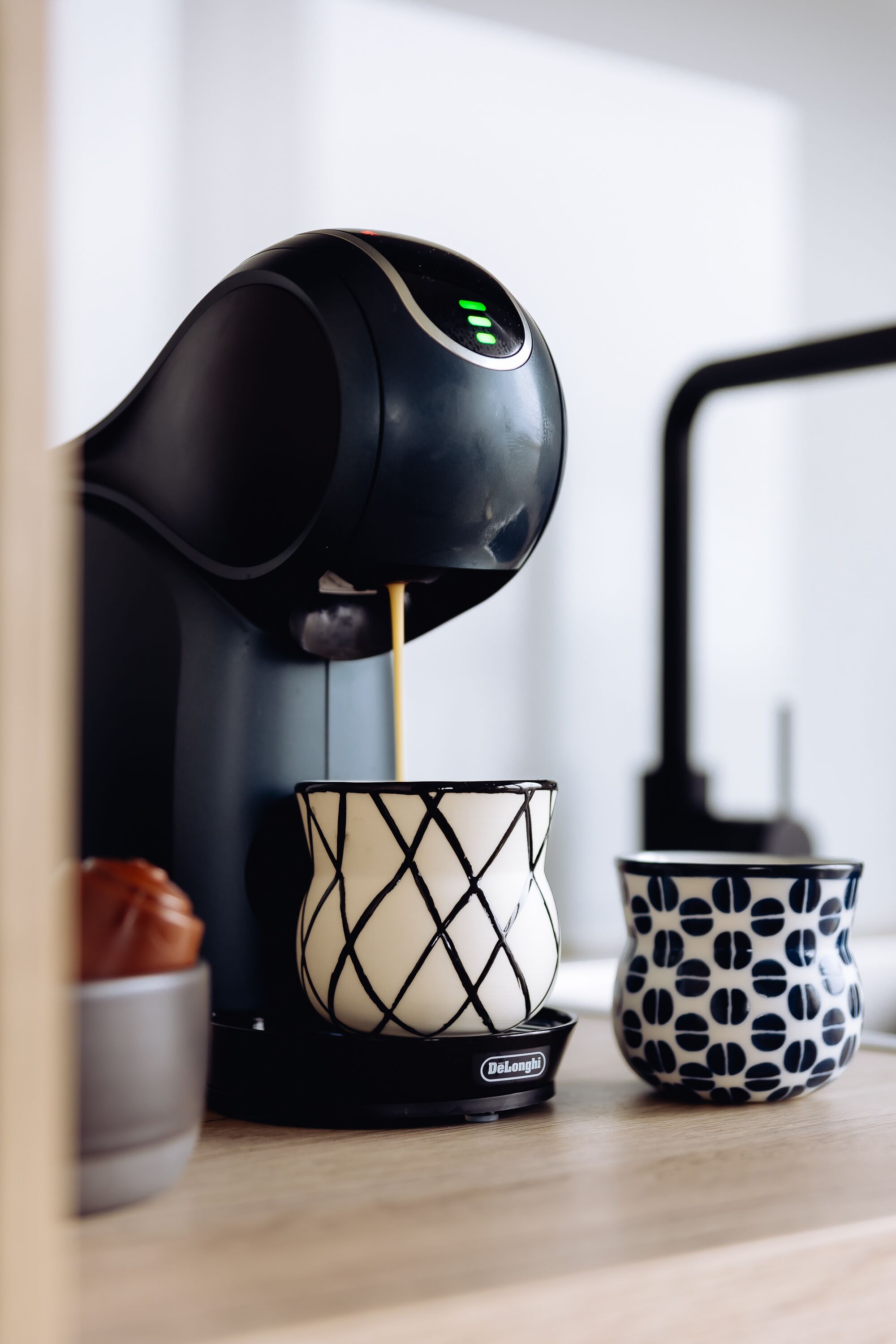 Una macchina da caffè che eroga caffè in una tazza con un motivo geometrico.