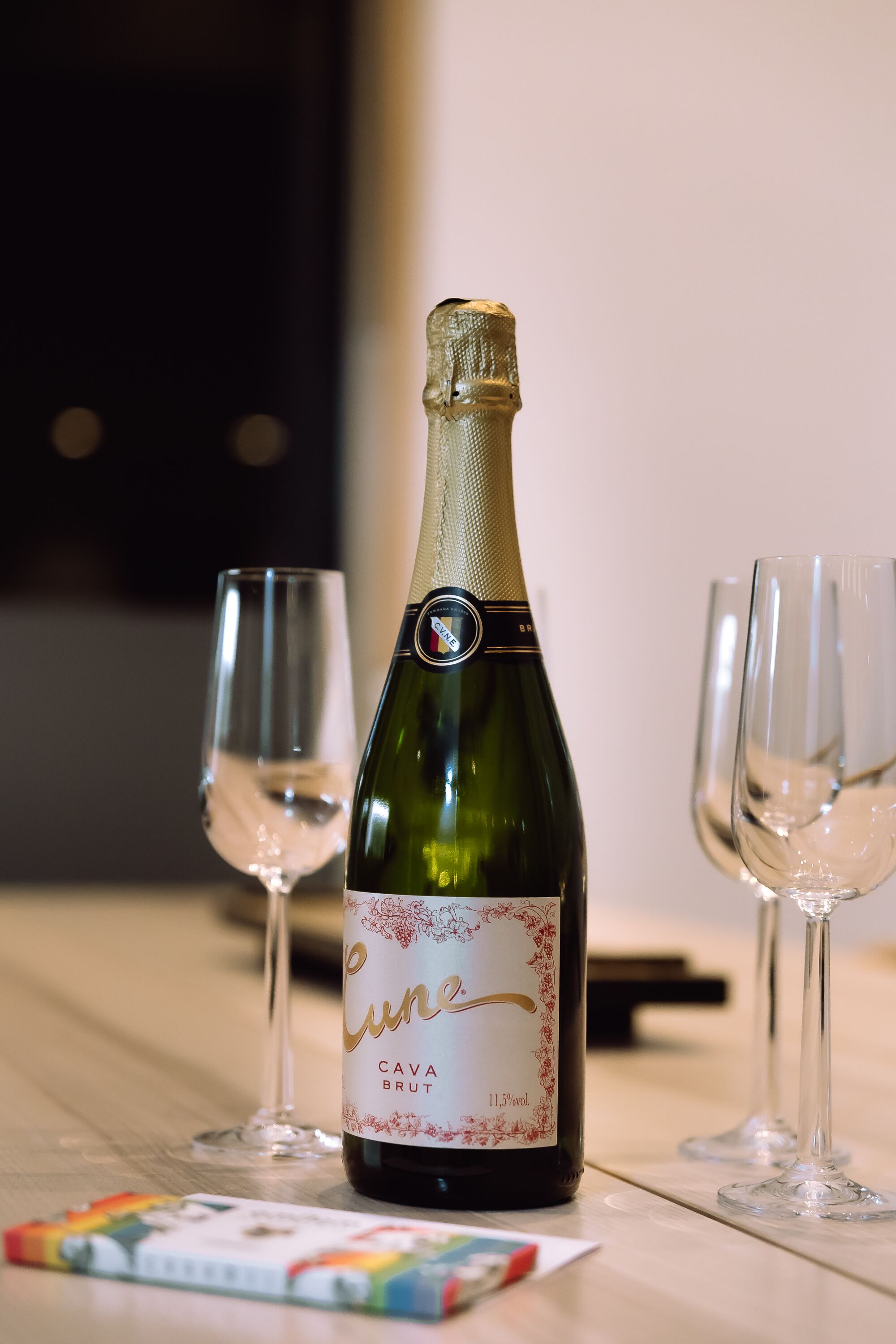 Una botella de vino Cava Brut y dos copas de vino vacías sobre una mesa.