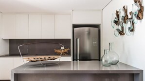 Een moderne keuken met witte kasten, een roestvrijstalen koelkast en een centraal eiland met een geweven mand.