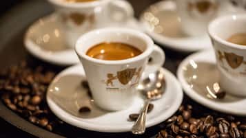A tray with several white coffee cups and saucers, each with a lion emblem, surrounded by coffee beans.