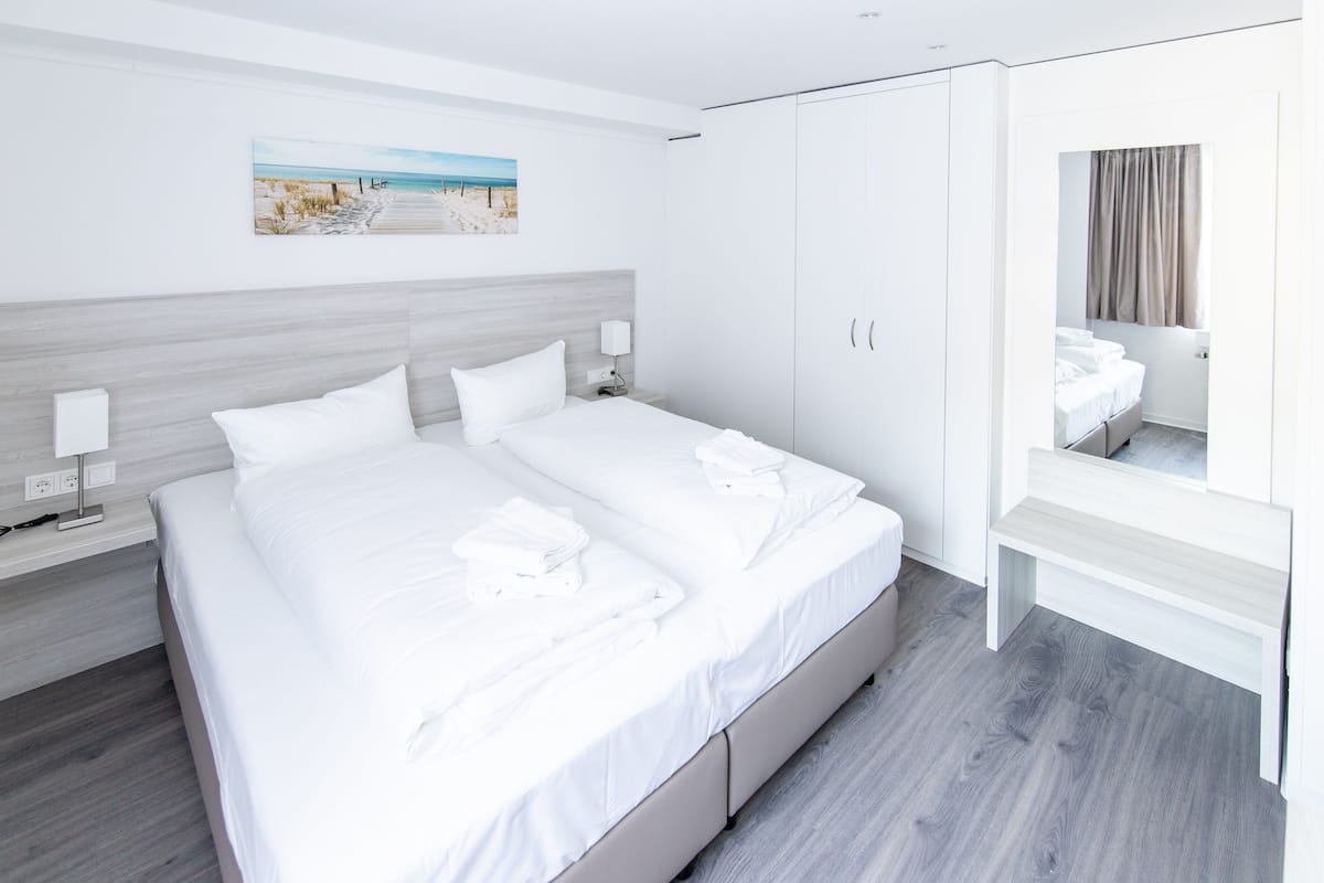 Una camera d'albergo con un letto, comodini, uno specchio e un quadro appeso al muro.