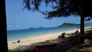 A beach with clear blue water, a sandy shore, and a few people.