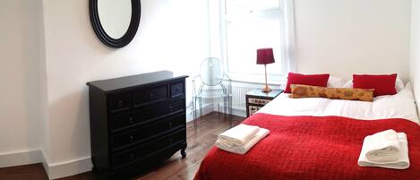A bedroom with a bed, a dresser, a chair, and a window.