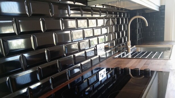 A kitchen with a black backsplash, stainless steel sink, and a black stovetop. - Victorian Terraced Apartments (London)