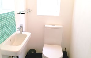 Un bagno piccolo con un lavandino bianco, un water e una finestra sopra il water.