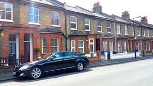 A row of terraced houses with a black car parked in front. - Victorian Terraced Apartments (London)