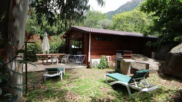 Eine Holzdiele mit einer Terrassenfläche, Sitzgelegenheiten im Freien und Blick auf den umliegenden Wald.