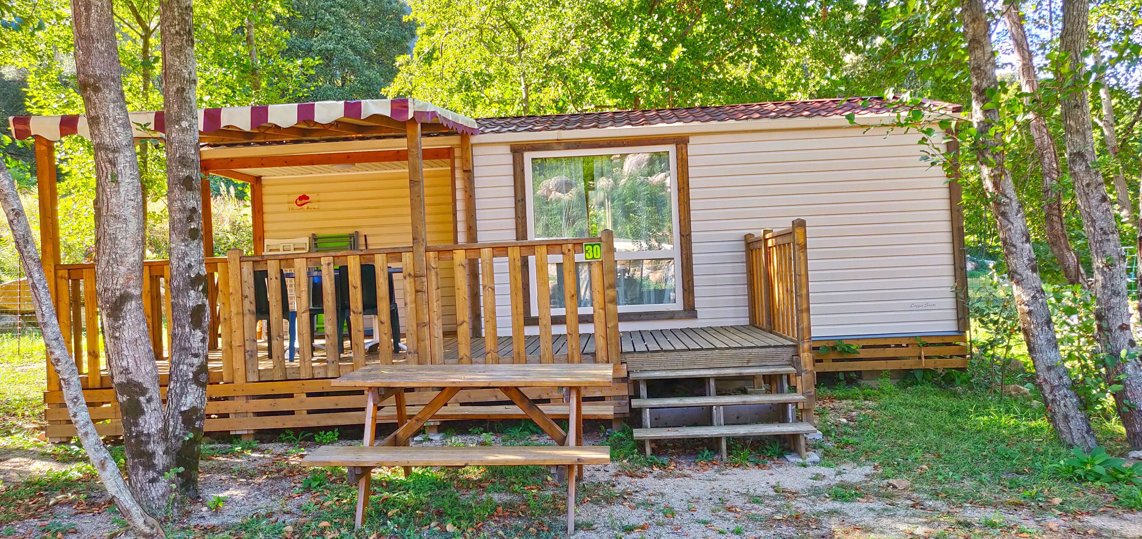 Una cabaña de madera con un porche, una terraza y una pequeña escalera que lleva a una ventana.