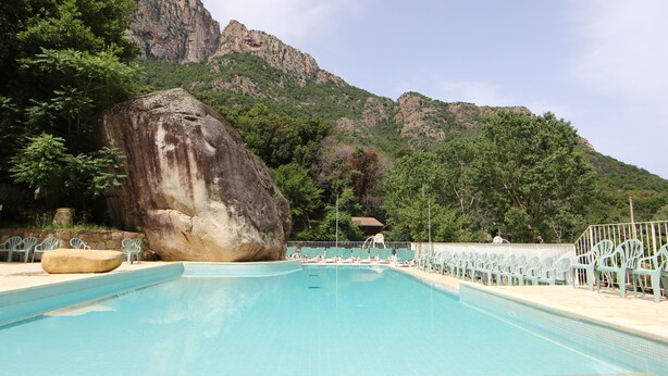 A swimming pool with lounge chairs, a large rock, and a mountain backdrop. - Funtana a l'ora (Ota)