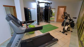 Un gimnasio con cinta de correr, bicicleta estática y máquinas de pesas.