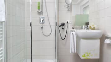A modern bathroom with a glass-enclosed shower, a white sink, and a mirror.