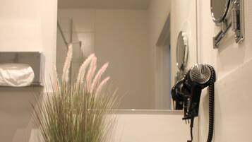 A bathroom with a granite countertop, a potted plant, two towels, a hairdryer, and a mirror.