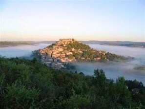 Un pueblo montañoso con edificios ubicados entre árboles y niebla.