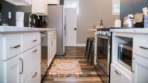 A modern kitchen with white cabinetry, a central island, and a patterned rug. - Joanna Gaines would stay here! (Sandpoint)