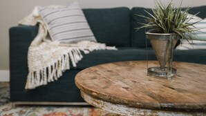 A round wooden coffee table with a plant in a metal pot. - Joanna Gaines would stay here! (Sandpoint)
