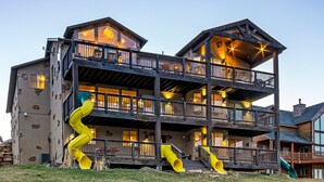 Un edificio de varios pisos con fachada de madera, balcones y un tobogán.
