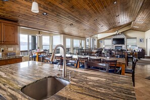 A spacious kitchen with a large island, wooden ceiling, and a fireplace.